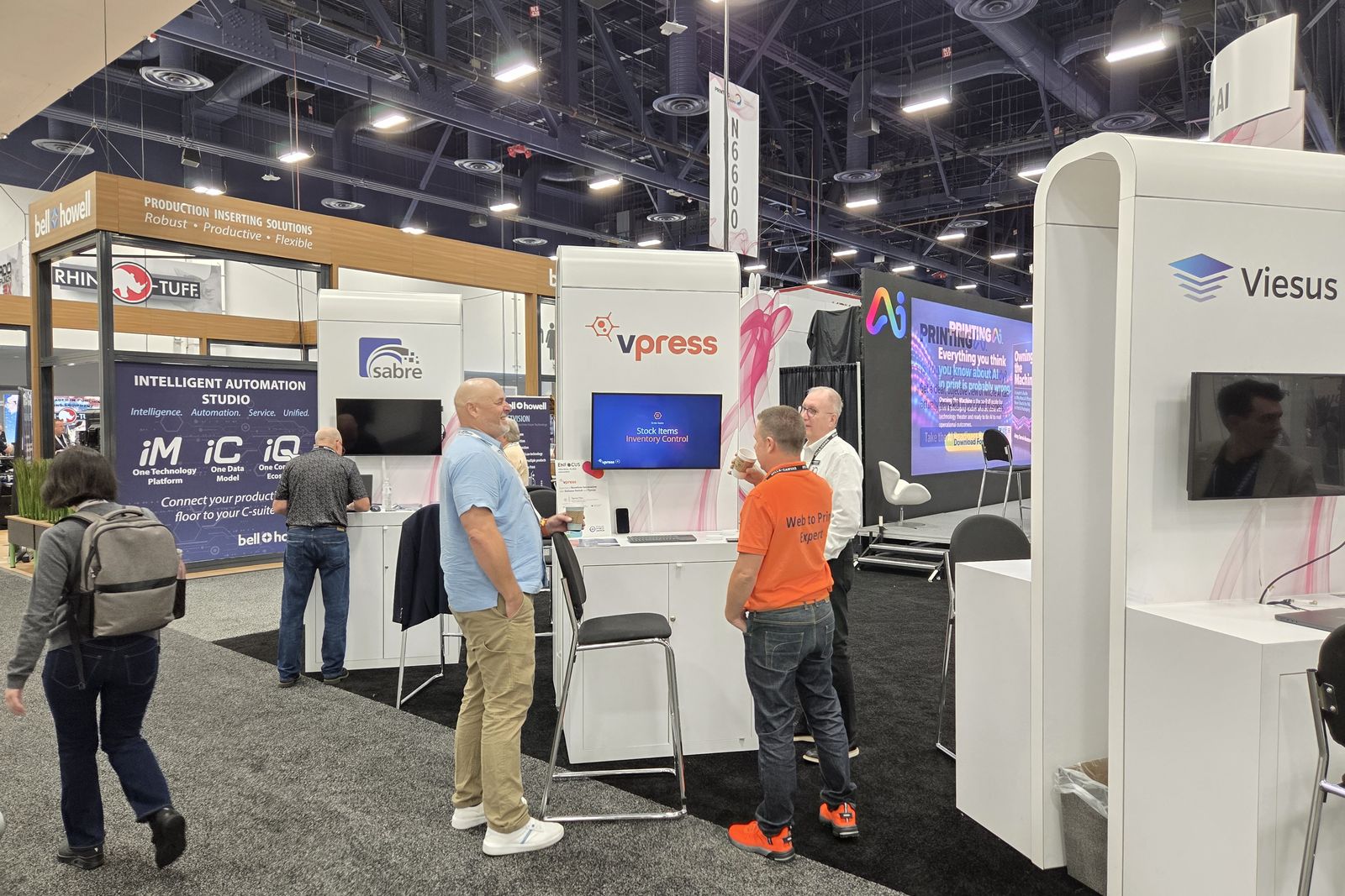 The Vpress pod in the PRINTING AI Pavilion at PRINTING United Expo 2026, with visitors talking to the team