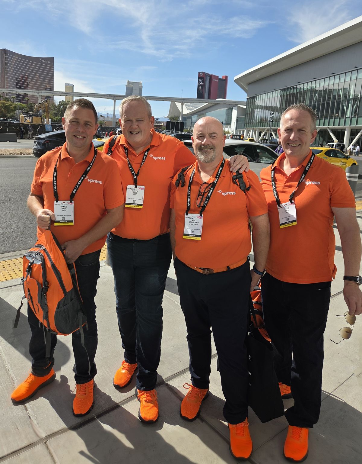 Four of the Vpress team in orange polo shirts and orange trainers in Las Vegas for PRINTING United Expo 2026